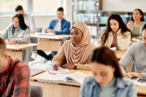 African American Islamic student takes notes while attending a lecture at university.